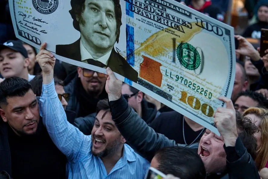 Apoiadores de Javier Milei levantam bandeira com sua imagem estampada em uma nota de dinheiro — Foto: Hernan Zenteno / La nacion / GDA
