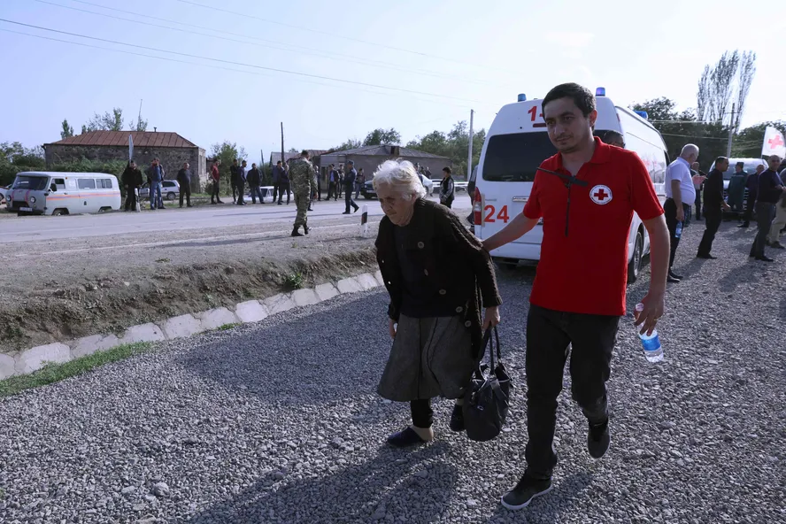 Um funcionário da Cruz Vermelha cuida de refugiada no centro de registro, em Kornidzor, após cruzar fronteira da Armênia